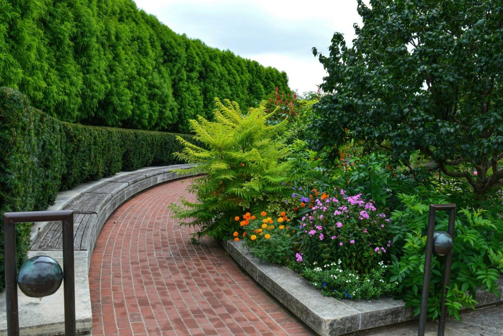 ein Ziegelweg mit einem Garten aus Blumen und Bäumen